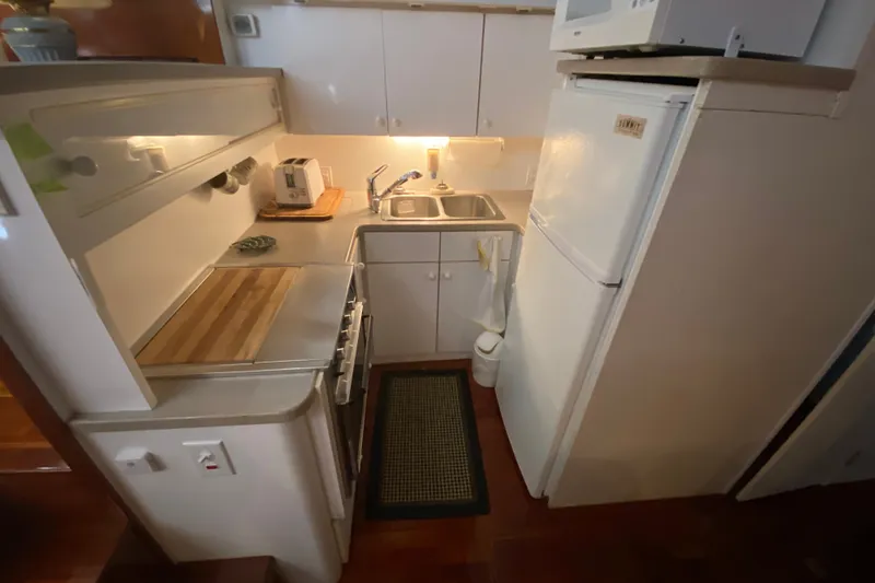 Slide: The Image of Compact kitchen in a 1995 Silverton 41 Convertible yacht with appliances and wooden countertop. - 14
