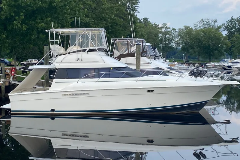 Slide: The Image of 1995 Silverton 41 Convertible yacht docked at a marina, reflecting on calm water. - 2