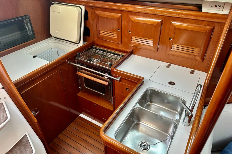 Slide: The Image of Galley kitchen in 2004 Beneteau Oceanis Clipper 393 yacht with wood cabinetry and stainless steel sink. - 18