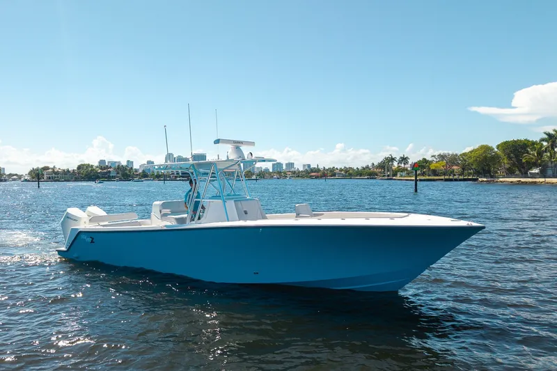 Slide: The Image of 2025 SeaVee 322Z boat cruising on a sunny day, with city skyline in the background. - 2