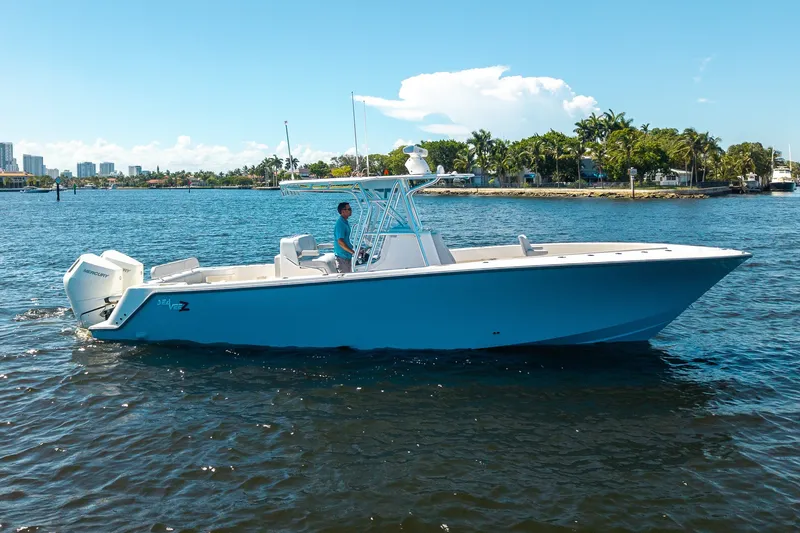 The Image of 2025 SeaVee 322Z boat cruising on a sunny day near a tropical shoreline. - 1