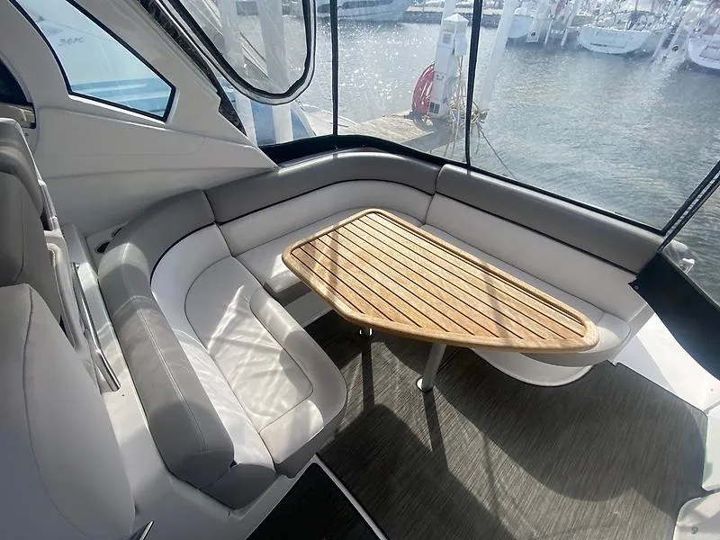 Slide: The Image of Interior of a 2018 Four Winns 355 Vista with gray upholstery and a wooden table. - 8