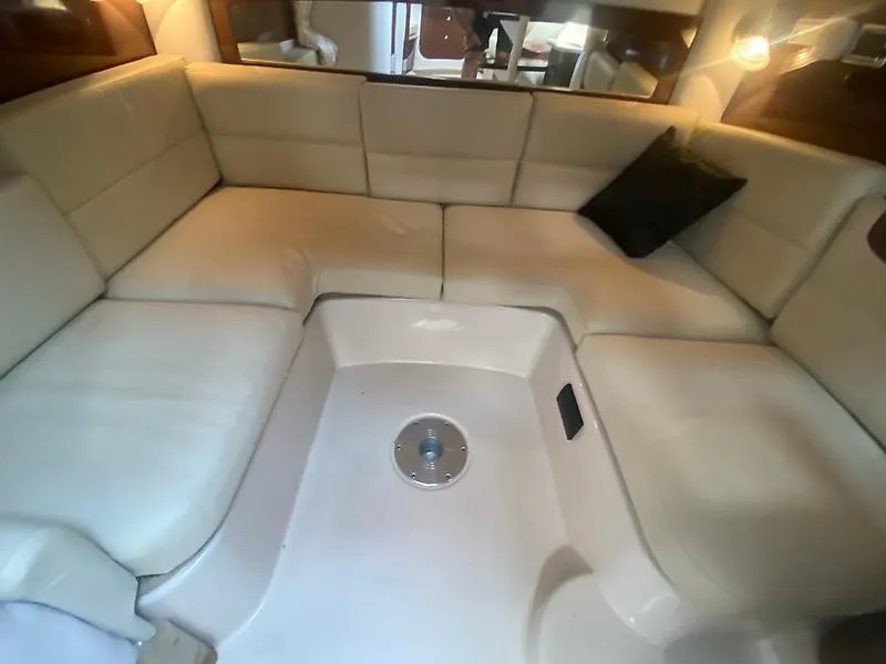 Slide: The Image of Interior of the 2018 Four Winns 355 Vista with beige upholstered seating and a central table base. - 19