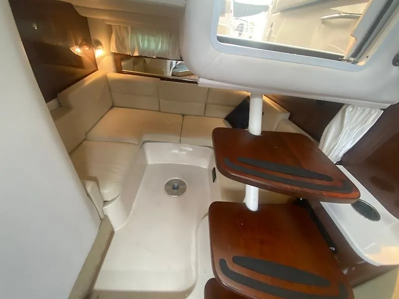 Slide: The Image of Interior of the 2018 Four Winns 355 Vista with beige sofa and wooden table. - 4