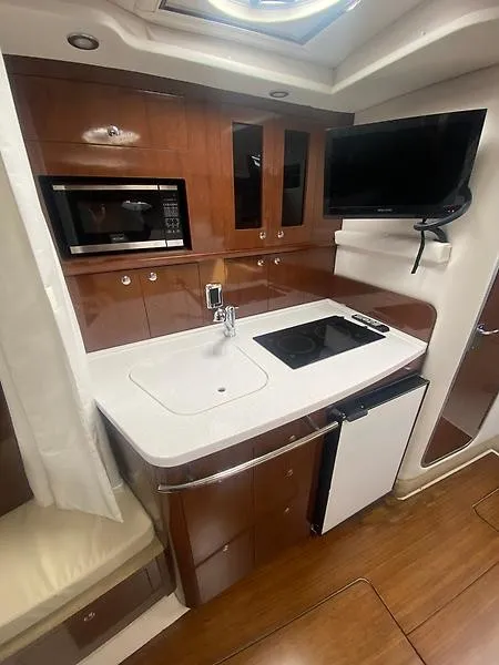 Slide: The Image of The 2018 Four Winns 355 Vista kitchen features a sink, stove, and television. - 3