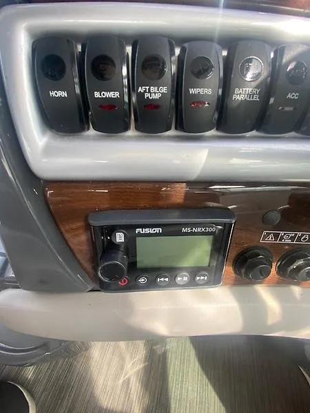 Slide: The Image of The image shows the dashboard of a Four Winns 355 Vista boat with various switches and a Fusion MS-NRX300 radio. - 14