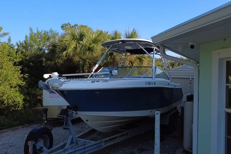 Slide: The Image of 2012 Robalo R247 Dual Console boat on trailer near house and trees. - 1