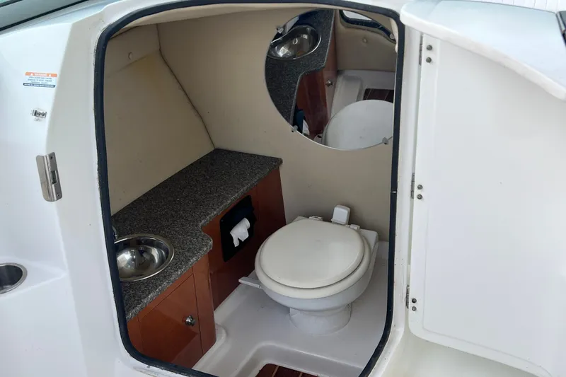 Slide: The Image of 2012 Robalo R247 Dual Console boat bathroom with toilet, sink, and mirror. - 27