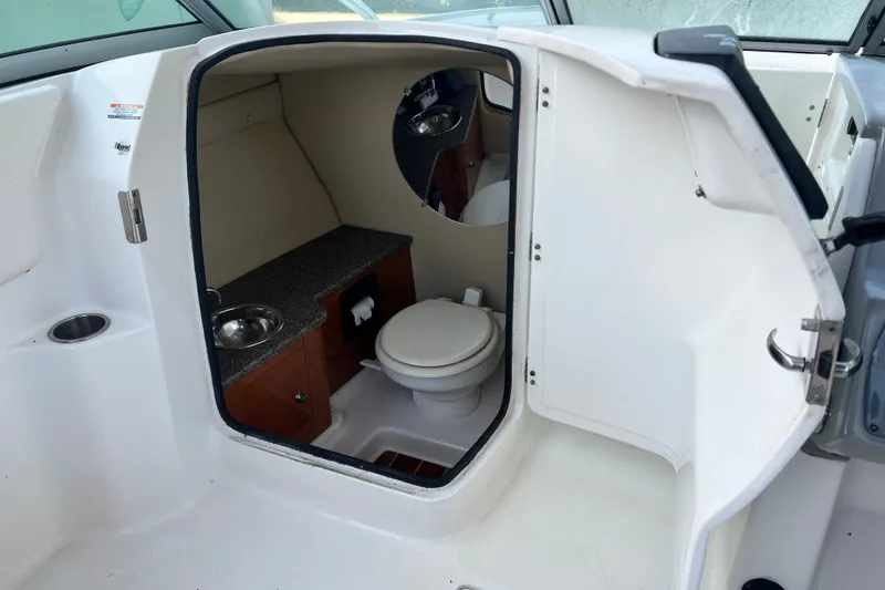 Slide: The Image of 2012 Robalo R247 Dual Console boat interior with compact bathroom and sink. - 28