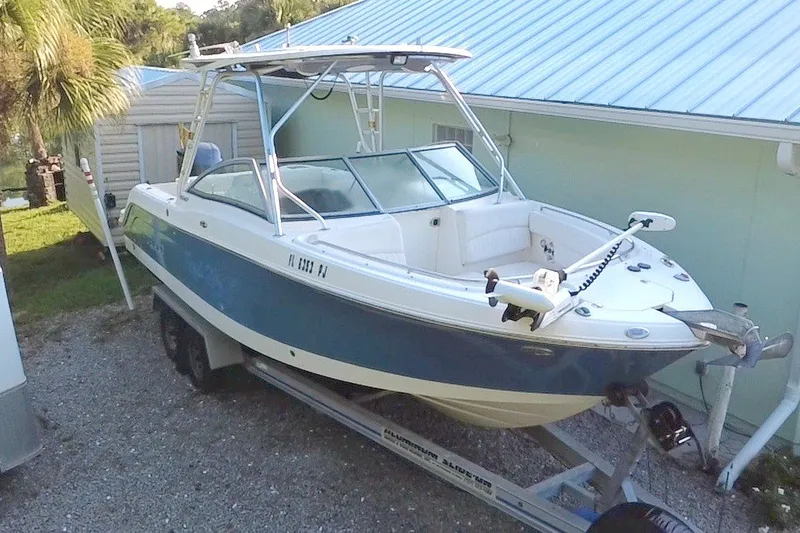 Slide: The Image of 2012 Robalo R247 Dual Console boat on trailer, parked beside a house with palm trees. - 5