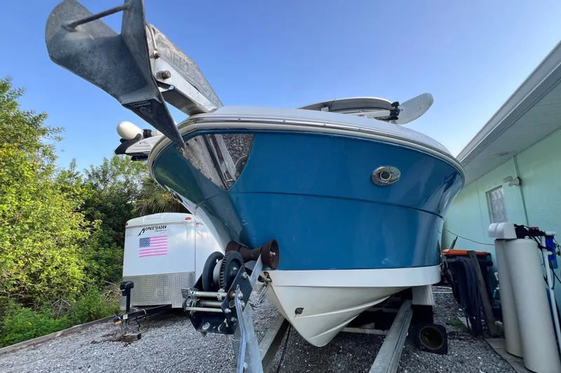 Slide: The Image of 2012 Robalo R247 Dual Console boat on trailer, blue hull, parked outdoors. - 2