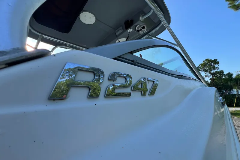 Slide: The Image of 2012 Robalo R247 Dual Console boat with chrome emblem, clear sky background. - 16