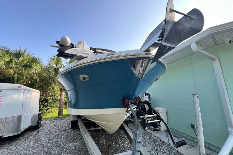 Slide: The Image of 2012 Robalo R247 Dual Console boat on trailer, blue hull, parked near palm trees. - 4