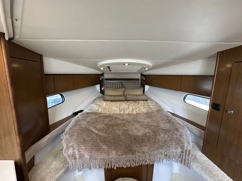 Slide: The Image of Cabin of the 2017 Cruisers Yachts 350 Express with a cozy bed and wood accents. - 19