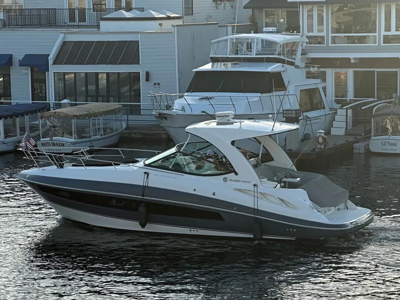 The Image of A 2017 Cruisers Yachts 350 Express is docked in the water near piers and buildings. - 0