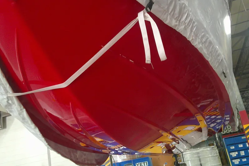 Slide: The Image of Red 2026 Tahoe T18 boat hull wrapped in protective cover in a storage facility. - 2
