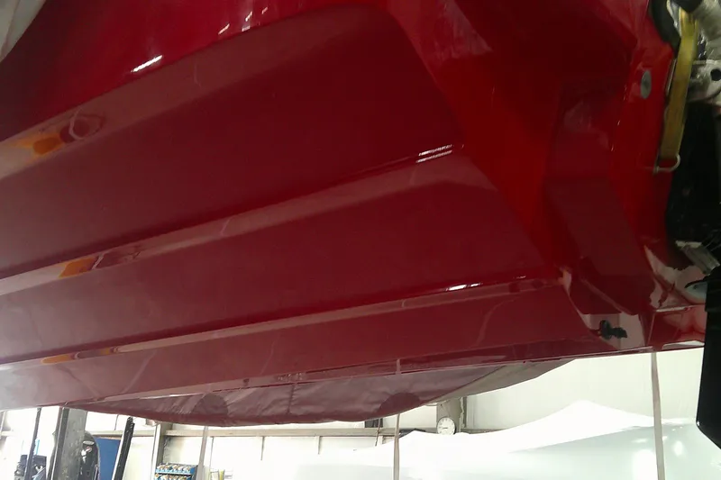 Slide: The Image of Red hull of a 2026 Tahoe T18 boat in a workshop setting. - 1