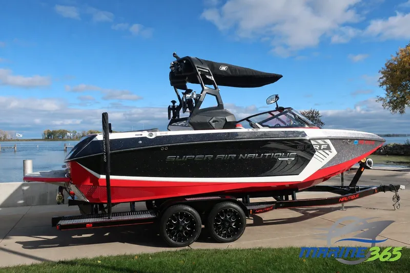 The Image of 2019 Nautique Super Air Nautique G23 boat on trailer by a lake under blue sky. - 0