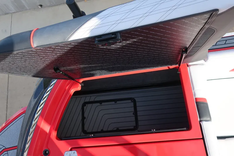Slide: The Image of 2019 Nautique Super Air Nautique G23 storage compartment with open hatch, red and black design. - 12