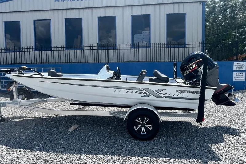 The Image of 2027 Xpress H18 Bass boat on trailer, parked outside a building. - 1