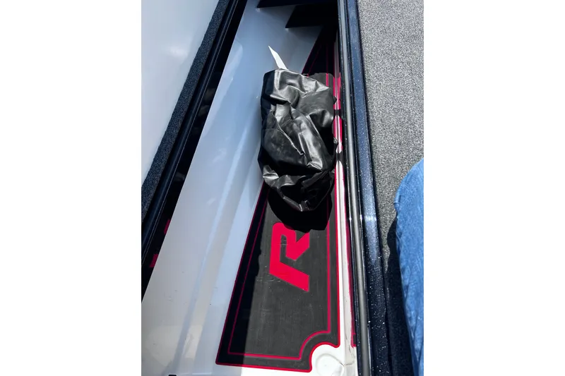 Slide: The Image of 2024 Ranger Z520R boat compartment with black and red mat, and a black bag. - 19