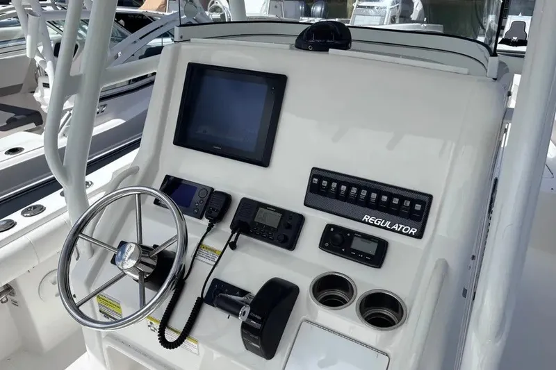 Slide: The Image of 2014 Regulator 23 Forward Seating boat dashboard with steering wheel and electronic controls. - 13