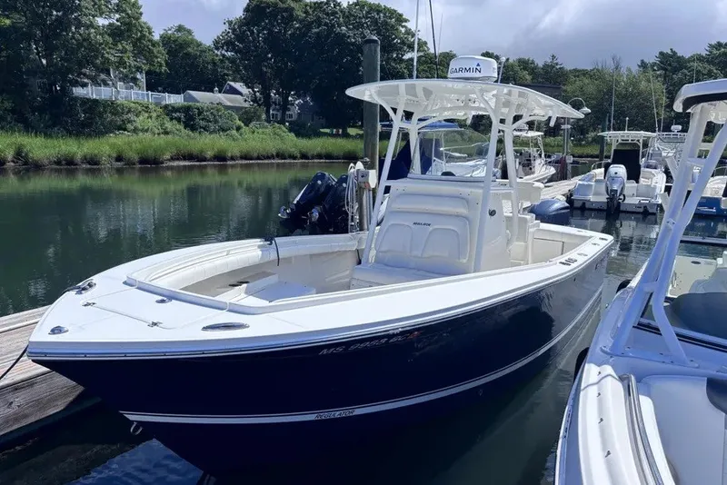 Slide: The Image of A 2014 Regulator 23 Forward Seating boat docked in a calm marina. - 1