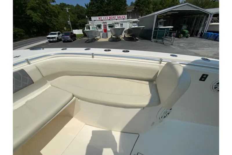 Slide: The Image of 2018 Cobia 301 Center Console boat interior with beige seating at a boat dealership. - 26