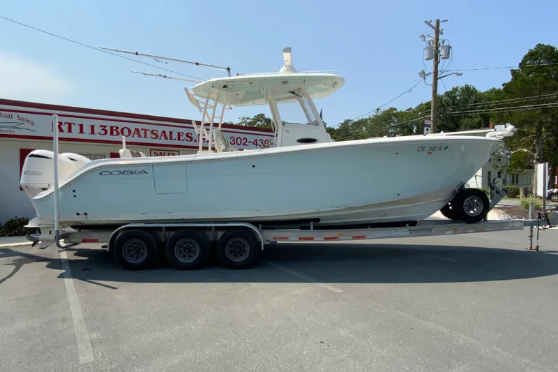 The Image of 2018 Cobia 301 Center Console boat on a trailer at a dealership. - 1