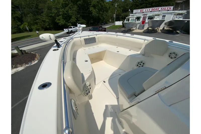 Slide: The Image of 2018 Cobia 301 Center Console boat interior at dealership, showcasing seating and speakers. - 19