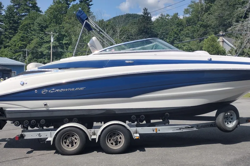 Slide: The Image of 2013 Crownline Eclipse E4 boat on trailer, blue and white design, parked outdoors. - 5