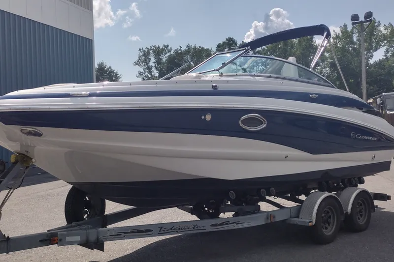 Slide: The Image of 2013 Crownline Eclipse E4 boat on trailer, blue and white design, parked outdoors. - 2