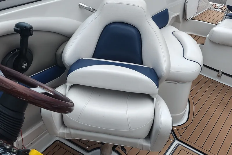 Slide: The Image of 2013 Crownline Eclipse E4 boat interior with white and blue captain's chair and wooden steering wheel. - 14