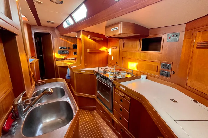 Slide: The Image of Interior of 1986 Baltic 48 DP yacht, featuring a well-equipped wooden galley kitchen. - 22