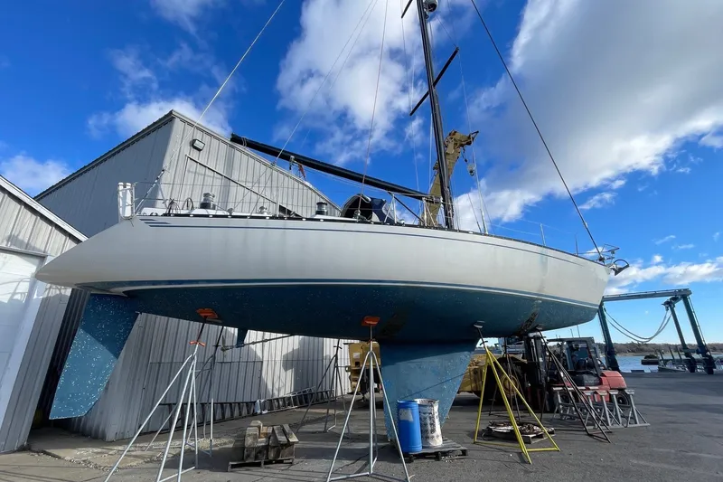 Slide: The Image of 1986 Baltic 48 DP sailboat on dry dock, showcasing hull and keel under clear blue sky. - 31