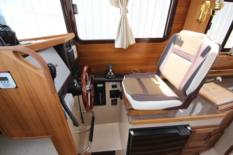 Slide: The Image of Interior of a 2015 Ranger Tugs R-27 with wood paneling and steering wheel. - 32