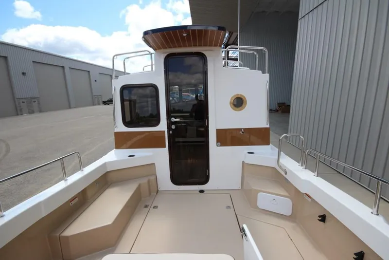 Slide: The Image of The image shows the stern of a 2015 Ranger Tugs R-27 with seating and a cabin door. - 15
