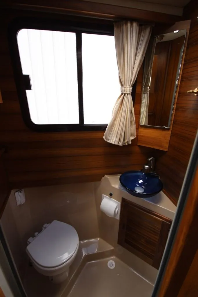 Slide: The Image of The 2015 Ranger Tugs R-27 bathroom features a toilet, sink, and window. - 37