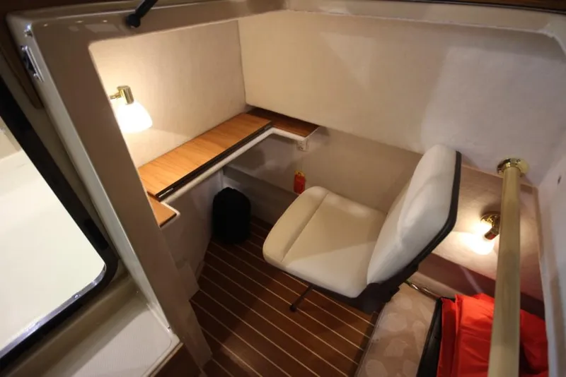 Slide: The Image of The interior of a 2015 Ranger Tugs R-27 features a cozy workspace with a chair and wooden flooring. - 30
