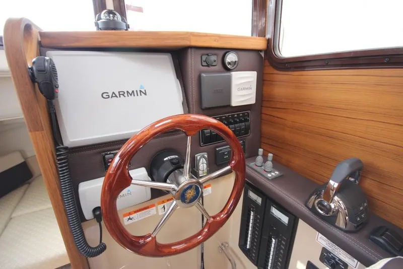 Slide: The Image of The cockpit of a 2015 Ranger Tugs R-27 with a Garmin navigation system and wooden steering wheel. - 28