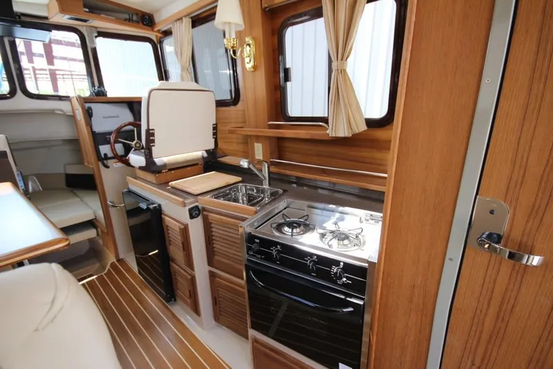 Slide: The Image of Interior of a 2015 Ranger Tugs R-27 featuring a kitchen and helm area. - 35