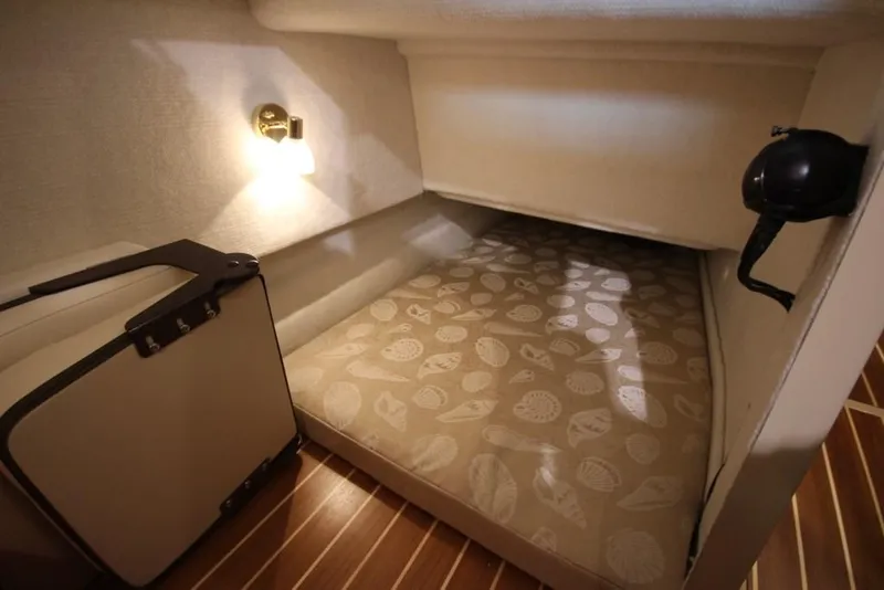 Slide: The Image of The 2015 Ranger Tugs R-27 cabin features a cozy bed with patterned cover and wooden flooring. - 38