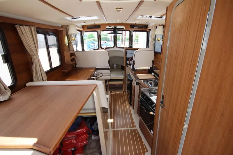 Slide: The Image of Interior of a 2015 Ranger Tugs R-27 with wood flooring, kitchen, and seating area. - 36