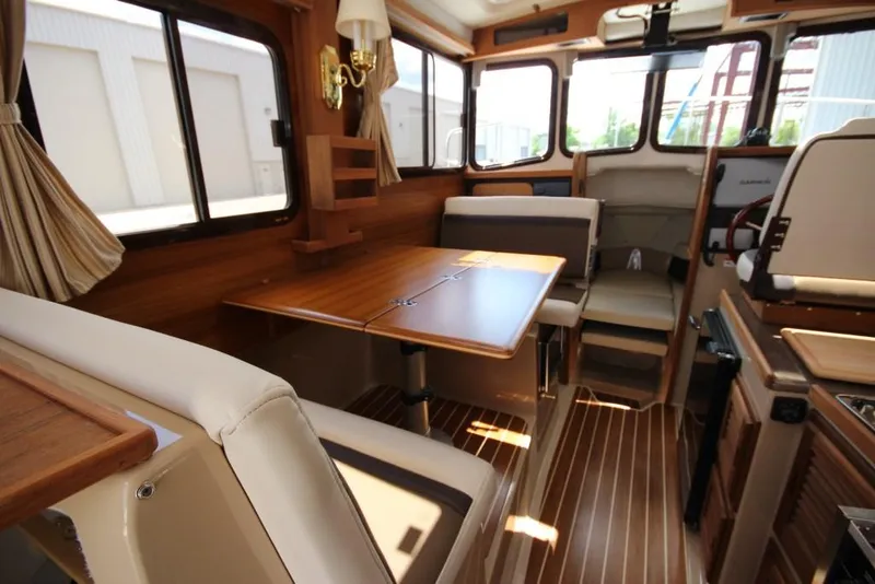 Slide: The Image of Interior of a 2015 Ranger Tugs R-27 with a wooden table and seating area. - 26