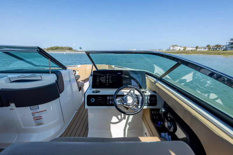 Slide: The Image of 2022 Sea Ray SLX 280 boat interior with steering wheel and dashboard, cruising on calm waters. - 14
