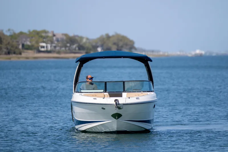 Slide: The Image of 2022 Sea Ray SLX 280 boat cruising on a calm lake with a blue canopy. - 3