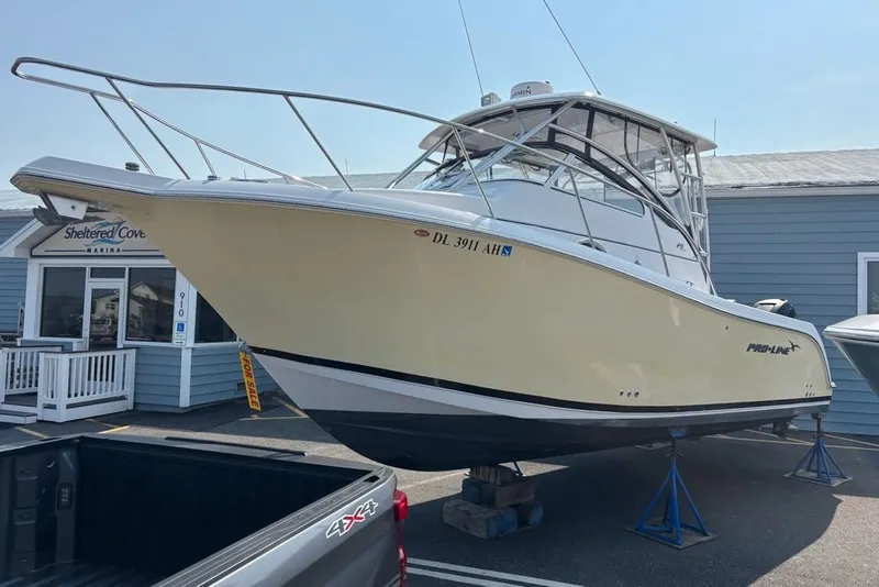 The Image of 2007 Pro-Line 29 Express boat on stands at marina, for sale sign visible. - 0