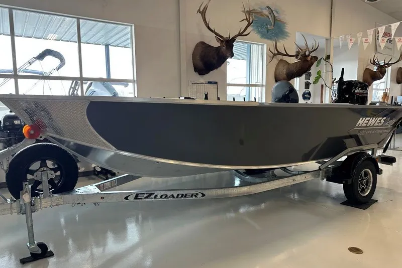 Slide: The Image of 2026 Hewescraft 180 Open Fisherman boat on EZ Loader trailer in showroom. - 1