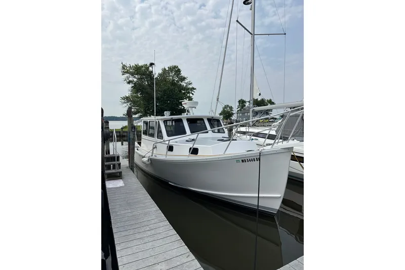 Slide: The Image of White 2001 Willis Beal 31 boat docked at a marina under a cloudy sky. - 1