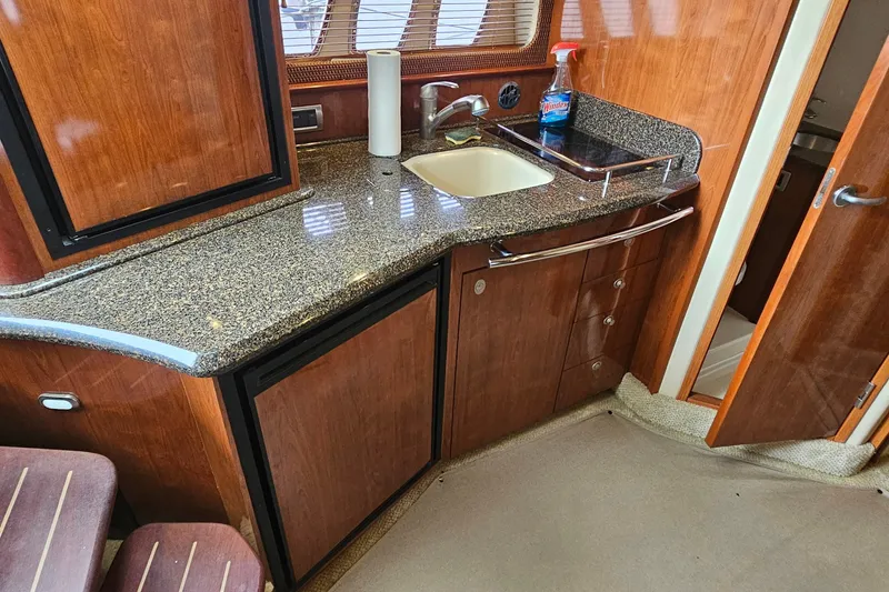 Slide: The Image of 2004 Sea Ray 380 Sundancer galley with granite countertop and wooden cabinetry. - 9